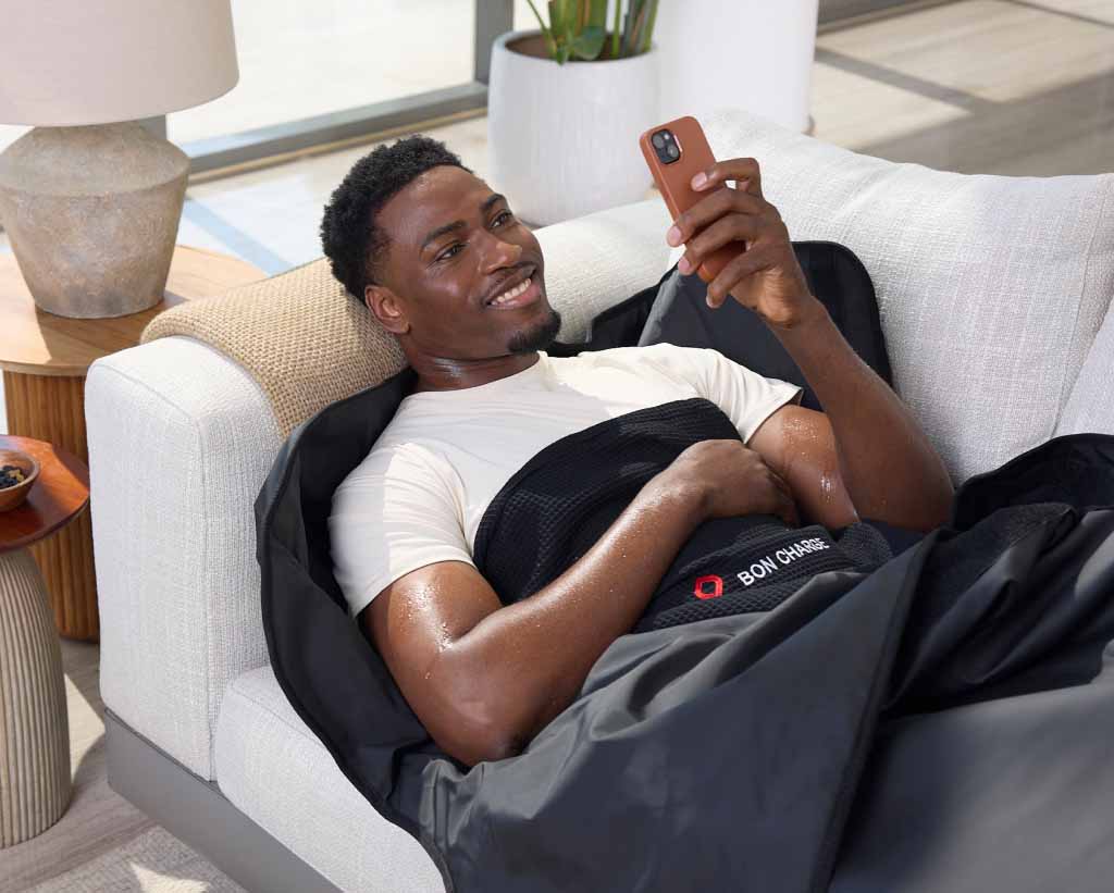 Male Laying On Sofa In Sauna Blanket Scrolling On Phone